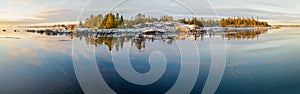 Panoramic view of Scenic Winter Sunset Reflections From Iced Sea to small stony peninsula Kont, Umea, Sweden. Winter scandinavian