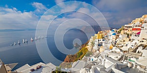 Panoramic view of the sights of Santorini  The famous town of Oia in the morning. A line of sailing yachts at sea. Good vacation.