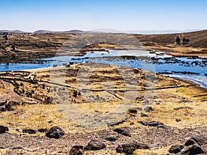 Panoramic view of Sillustani archeological site with arid lands and lagoon populated by flamingos, Puno region, Peru