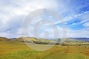 Panoramic view from the slopes of the Terevaka Volcano on Easter Island, showing green vegetation and the ocean against