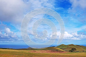 Panoramic view from the slopes of the Terevaka Volcano on Easter Island, showing green vegetation and the ocean against