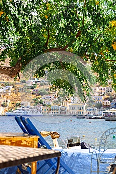 Panoramic view, of small haven of Symi island. Village with Street Cafe and colorful houses located on rock.