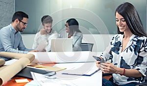 Panoramic view of smiling business woman using phone near office desk with colleagues in the background