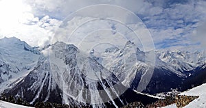 Panoramic view of snowy mountains peaks in the clouds blue sky Caucasus