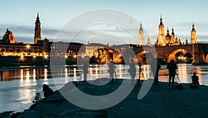 Panoramic view of some photographers in front of Basilica del Pilar, Puente de Piedra and Catedral de la Seo at sunset in Zaragoza