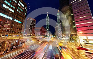 Panoramic view of a street corner in Downtown Taipei City with busy traffic trails at rush hour