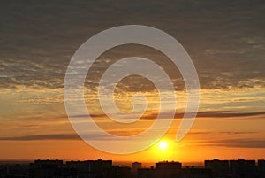 A panoramic view of the stunningly beautiful sunset over the city blocks and chic cirrus clouds, illuminated by the sun