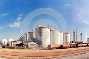 Panoramic view of a sugar factory\'s exterior, with storage silos, smokestacks, and a network of pipes and conveyors photo