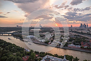 Panoramic view of sunset above Moscow city and cloud reflections in river with traveling boats