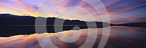 Panoramic view at sunset of flooded salt flats and Panamint Range Mountains in Death Valley National Park, California