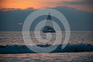 Panoramic view of sunset over ocean. Sailboat on the sea. Sailing boat floating on the blue ocean during sunrise with