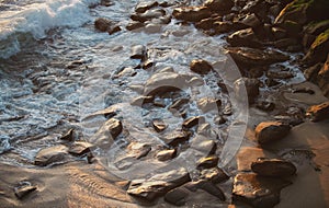 Panoramic view of sunset over ocean. Sea waves lash line impact rock on the beach.