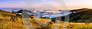 Panoramic view at sunset of valley covered in a sea of clouds in the Santa Cruz mountains, San Francisco bay area, California