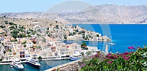 Panoramic view on tiny colorful houses on rocks and big boats on harbor near the Mediterranian sea on Greek island in sunny summer photo