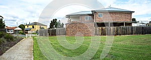 Panoramic view of a vacant land next to a two-story residential house.