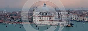 Panoramic view of Venice skyline at dusk on a clear day showing the Basilica di Santa Maria della Salute and Grand Canal