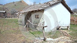 Panoramic view of village. Old dilapidated black wooden boat with a one-storey house, a well and a hill. Old wooden
