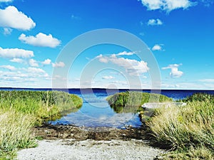 Panoramic view of a watet body with costline against blue sky with clouds