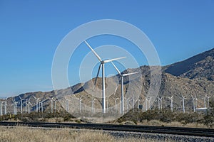 Panoramic view of windmills and railroad with clear blue sky and mountains