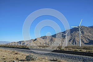 Panoramic view of windmills or windpumps along railroad on a sunny day