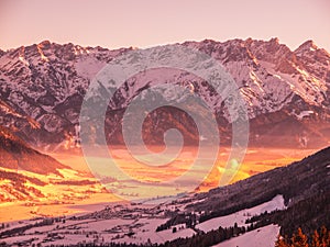 Panoramic view of winter mountains. Alpine peaks and valley in morning fog