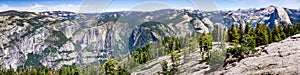 Panoramic view in Yosemite National Park with Yosemite falls on the right and Half Dome on the left; snow covered peaks visible in