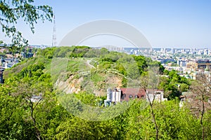 Panoramic view of the Zamkova Hora Castle Hill or mount in Kyiv covered with greenery. In the background cityscape of Podil and photo