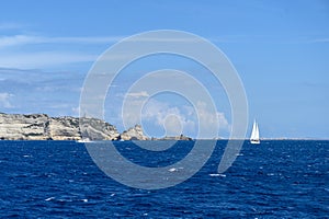 Panoramic views of the sea and rocks on a Sunny day. Sailing yacht with a white sail