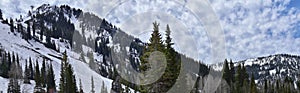 Panoramic Views of Wasatch Front Rocky Mountains from Little Cottonwood Canyon in early spring with melting snow, pine trees and b