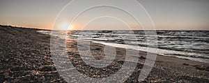 Panoramic waves of the Black Sea on the shore on the beach at a warm sunset and a rough sea with waves of foam and warm water