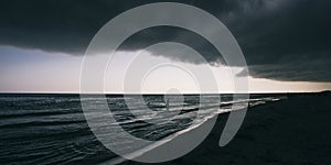 Panoramic widescreen view on the deep blue sea or ocean with dramatic toning on sunset. Big black hurricane clouds