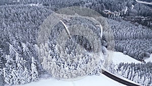 Panoramic winter drone view of the mountains in the forest. Cinematic winter snowy rural asphalt road.