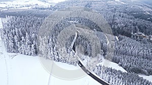 Panoramic winter drone view of the mountains in the forest. Cinematic winter snowy rural asphalt road.