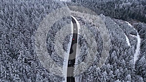 Panoramic winter drone view of the mountains in the forest. Cinematic winter snowy rural asphalt road.