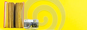 Panoramic yellow background of old analog camera with red book