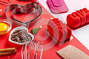 Pans hearts mold, whisk, eggs, wooden spatula and grated chocolate. Ingredients to making festive cake. Valentines Day bakeware