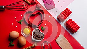 Pans hearts mold, whisk, eggs, wooden spatula and grated chocolate. Ingredients to making festive cake. Valentines Day bakeware