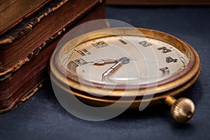 Panta rhei concept: antique pocket watch and pile of vintage hard cover books on natural stone