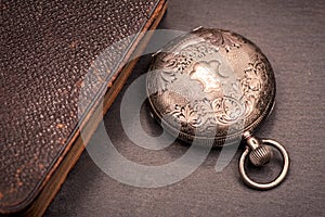 Panta rhei concept: antique pocket watch and pile of vintage hard cover books on natural stone