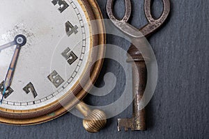 Panta rhei concept: old antique pocket watch and vintage key on natural stone