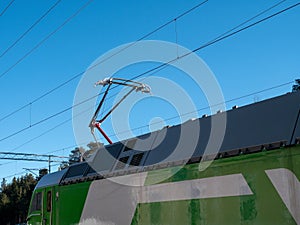 pantograph mounted on the roof of an electric train against blue sky