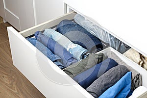 Pants folded according to the method of Marie Kondo. Vertical storage of clothes in a chest of drawers. Storage organization. photo