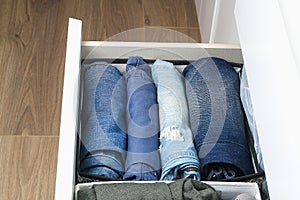 Pants folded according to the method of Marie Kondo. Vertical storage of clothes in a chest of drawers. Storage organization.