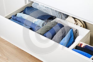 Pants folded according to the method of Marie Kondo. Vertical storage of clothes in a chest of drawers. Storage organization.