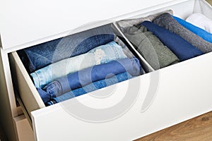 Pants folded according to the method of Marie Kondo. Vertical storage of clothes in a chest of drawers. Storage organization.