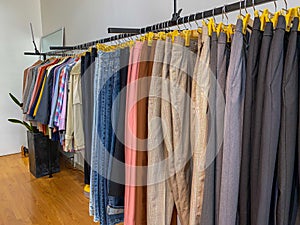 Pants and shirts hanging on shelf at clothing store