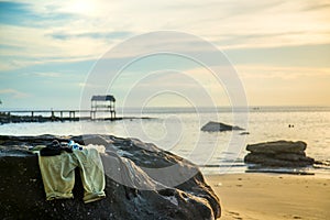 Pants, sunglass others accessories on stone at beach