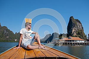 PANYEE ISLAND, THAILAND January 2020, wooden house on the water at the gypsy village in Phangnga Bay, men in longtail