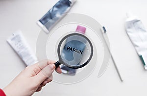 Papain in natural toothpaste. Magnifying glass is directed at a tube with a list of ingredients of a safe product. Safe toothpaste photo