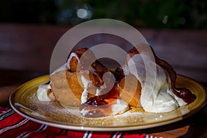 Papanasi - a traditional Romanian dessert. The cake is made from three donuts covered in sour cream and fruits jam